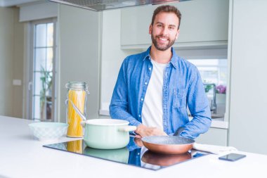 Yakışıklı adam yüzünde mutlu ve güzel bir gülümseme ile mutfak, İtalyan spagetti makarna pişirme. Şanslı kişi.