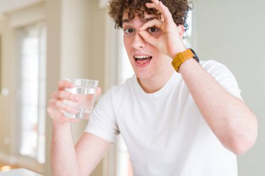 Genç adam mutlu yüz el parmaklarının arasından seyir göz üzerinde ok işaretiyle yapıyor gülümseyen ile evde su içme