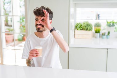 Genç adam bir kağıt bardak sabah el parmaklarının arasından seyir göz üzerinde ok işaretiyle yapıyor gülümseyen mutlu yüz ile bir kahve içme