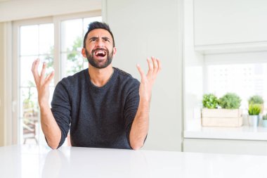 Casual kazak evde çılgın ve kızgın bağırarak ve agresif ifade ve silah kaldırdı bağırmaya giyen yakışıklı İspanyol adam. Hayal kırıklığı kavramı.