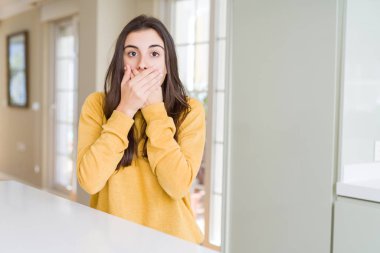 Sarı kazak ağız hata için elleriyle kapsayan şok giyen güzel genç kadın. Gizli kavramı.