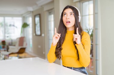 Müzik kulaklık giyen genç kadın hayrete ve yukarıya bakıyor ve parmakları ile işaret ve silah kaldırdı şaşırttı.