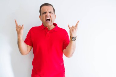 Orta yaş adam deli ifade rock simge elle yapıyor ile beyaz duvar bağırarak üzerinde kırmızı t-shirt giyiyor. Müzik yıldızı. Ağır kavramı.