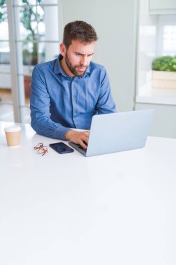 Yakışıklı iş adamı çalışma kullanma bilgisayar dizüstü ve gülümseyen