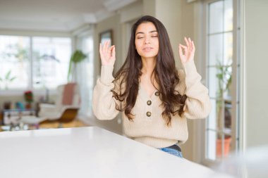 Genç güzel kadın evde dinlenin ve gülümseyen gözlerle parmak ile meditasyon jest yapıyor kapalı. Yoga kavramı.