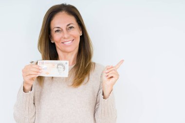 10 pound banknot izole arka plan üzerinde çok mutlu el ve parmak ile tarafına işaret tutan orta yaş kadın
