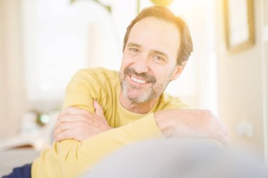 Rahat ve gülümseyen kanepede oturan yakışıklı orta yaş erkek 