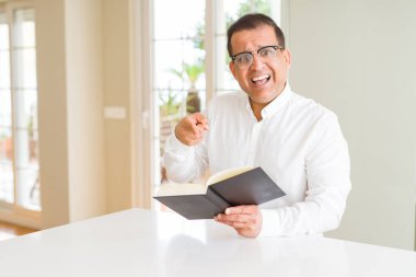 Gözlük el ve parmak ile çok mutlu işaret orta yaş erkek evde kitap okurken giyiyor