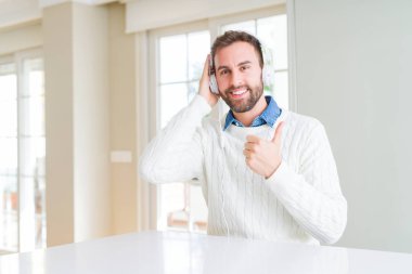 Kulaklık takmış ve mutlu ok işareti, başparmak ile parmak, mükemmel işareti yapıyor kocaman bir gülümseme ile müzik yakışıklı adam