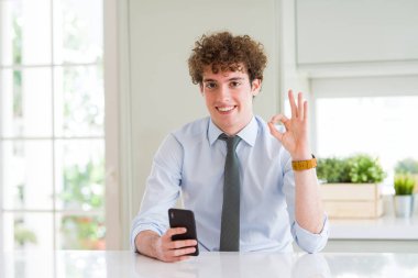 Parmak, mükemmel sembolü ile ok işareti yapıyor ofiste Smartphone kullanarak genç iş adamı