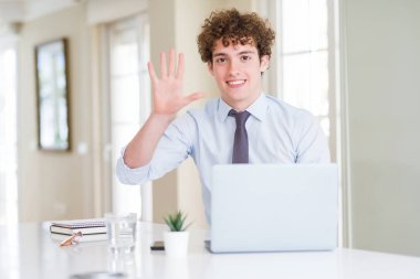 Bilgisayar laptop ile gösterilen ve parmakları ile işaret ofiste çalışan genç iş adamı kendinden emin ve mutlu gülümseyerek süre beş numara.