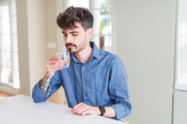 Genç adam ciddi düşünme akıllı yüzünde kendinden emin bir ifade ile su taze bir kadeh içmek