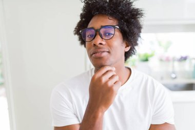 Afrika kökenli Amerikalı adam gözlüklü el ile çene düşünme hakkında soru, dalgın ifade üzerine. Düşünceli yüzüyle gülümsüyor. Şüphe kavramı.