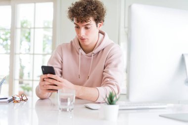 Acımak yüz ciddi düşünüyorum üstünde kendine güvenen bir ifade ile akıllı telefon ve bilgisayar kullanan genç öğrenci adam