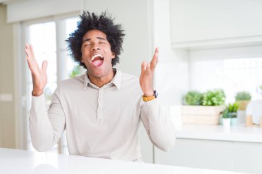 Afrika kökenli Amerikalı adam evde deli ve çığlık kaldırdı ve kapalı gözleri heyecanlı silah ile başarı için deli kutluyor. Kazanan kavramı