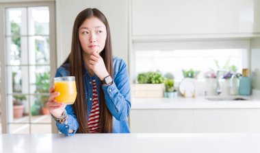 Bir bardak taze portakal suyu ciddi bir yüz düşünme hakkında soru, çok karışık fikir içme güzel Asyalı kadın