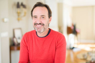 Evde kameraya bakarak gülümseyen yakışıklı orta yaş erkek