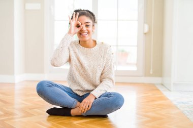 Gülümseyen, parmakları ile mutlu yüz üzerinden seyir göz el ile ok jest yapıyor katta oturan afro saçlı güzel genç Afro-Amerikan kadın.