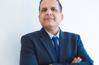 Beyaz duvar arka plan üzerinde seyir doğal ve rahat çapraz kolları olan orta yaş iş adamı