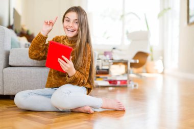 Güzel genç kız çocuk dijital touchpad kullanarak bir fikirle sürpriz katta oturan tablet veya gülen yüz, bir numara ile işaret parmağı soru