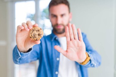 Yakışıklı adam çikolata kurabiye yeme dur işareti ile ciddi ve kendine güvenen ifade, savunma hareketi yaparken el açmak