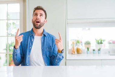 Yakışıklı adam evde hayret ve yukarıya bakıp parmakları ile işaret şaşırttı ve silah kaldırdı.