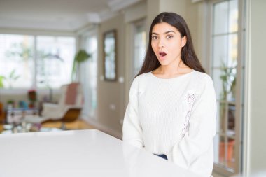 Genç güzel kadın evde beyaz tablo korkuyor ve sürpriz ifade, korku ve heyecan yüz ile şok.