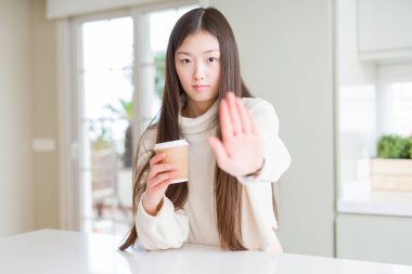 Güzel Asyalı kadın ile take away kağıt bardak kahve içme dur işareti ile ciddi ve kendine güvenen ifade, savunma hareketi yaparken el açmak