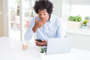 Hata, korku, sessizlik içinde gizli kavramı korkmuş ifade için el utanç ile şok ile smartphone ve laptop kapak ağzı kullanarak Afrika kökenli Amerikalı iş adamı
