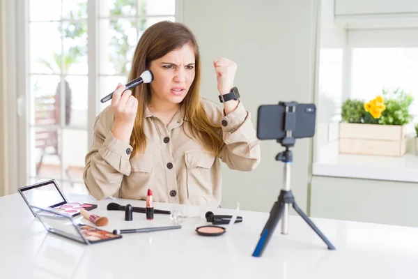 Beautiful young influencer woman recording make up video tutorial annoyed and frustrated shouting with anger, crazy and yelling with raised hand, anger concept