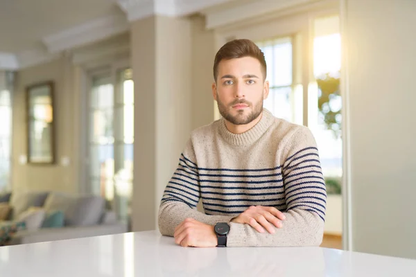 Young handsome man at home Relaxed with serious expression on face. Simple and natural looking at the camera.