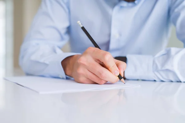 Primer plano de las manos del hombre escribiendo con un lápiz sobre papel sobre blanco —  Fotos de Stock