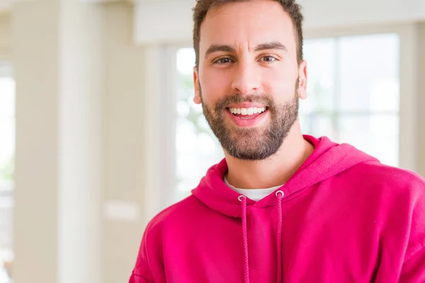 Hombre guapo vistiendo sudadera casual en casa y sonriendo — Foto de Stock