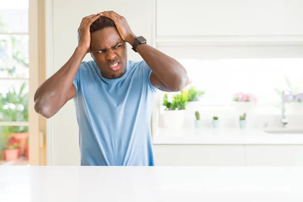 英俊的非洲裔美国人穿着休闲 T恤在家里遭受头痛绝望和压力 因为疼痛和偏头痛 双手放在头上 — 图库照片