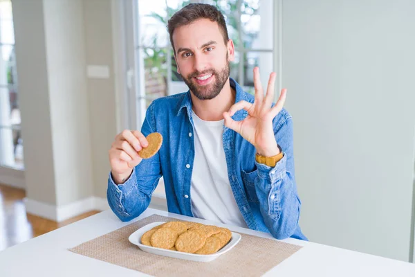 Όμορφος Άνθρωπος Τρώει Μπισκότο Υγιή Ολικής Αλέσεως Κάνει Εντάξει Πινακίδα — Φωτογραφία Αρχείου