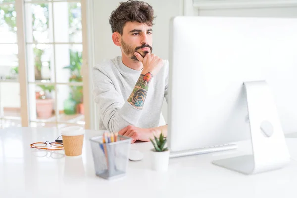Young man working using computer serious face thinking about question, very confused idea