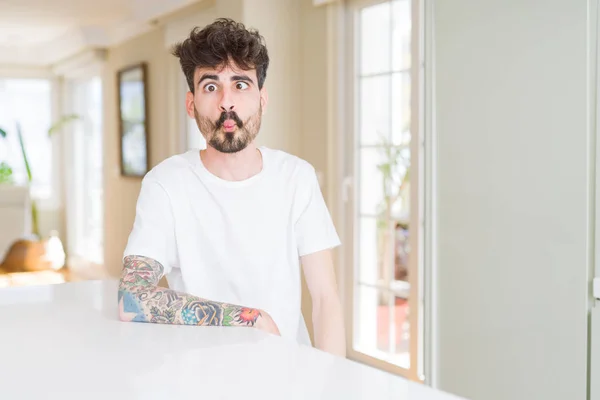 Hombre Joven Con Camiseta Casual Sentado Mesa Blanca Haciendo Cara — Foto de Stock