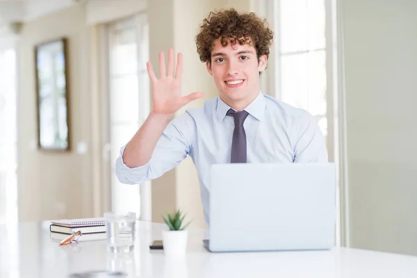 在办公室里用电脑笔记本电脑工作的年轻商人一边展示和用手指指着五号 一边面带微笑 自信而快乐 — 图库照片