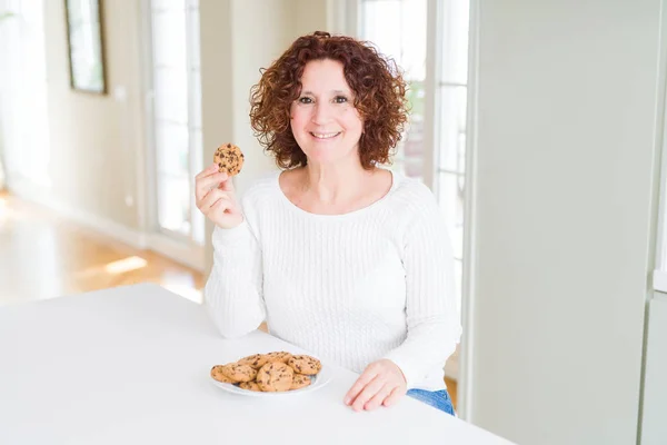 Ανώτερος Γυναίκα Τρώει Σοκολάτα Τσιπ Cookies Στο Σπίτι Ένα Χαρούμενο — Φωτογραφία Αρχείου