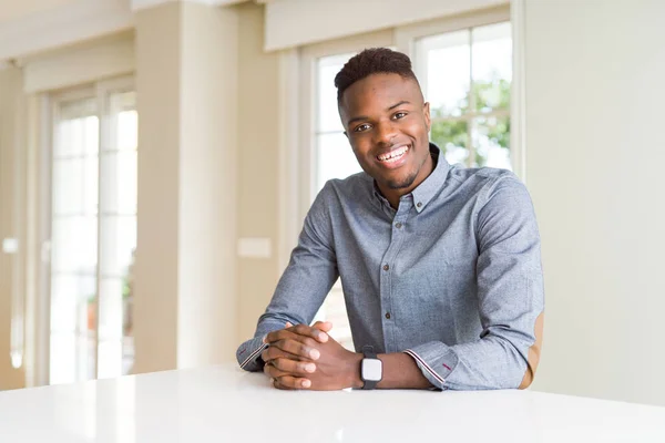 Handsome african american man on white table with a happy and cool smile on face. Lucky person.