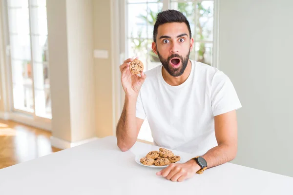 Όμορφος Άνδρας Ισπανόφωνος Τρώει Μπισκότα Τσιπ Σοκολάτας Φοβάται Σοκ Πρόσωπο — Φωτογραφία Αρχείου