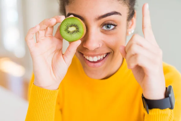年轻的非洲裔美国女孩吃绿色猕猴桃惊讶的想法或问题用快乐的脸指指点点 — 图库照片