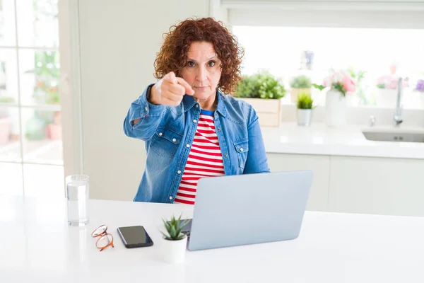 使用电脑笔记本电脑工作的高级妇女用手指指着相机和你 手的牌子 积极和自信的手势从前面 — 图库照片