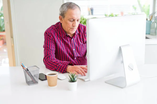 Hombre mayor guapo trabajando con computadora buscando concentrado — Foto de Stock