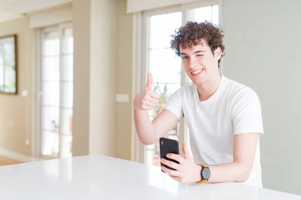 Akıllı Telefon Kullanan Genç Adam Evde Kocaman Bir Gülümseme Ile — Stok fotoğraf