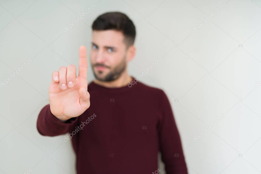 Young handsome man wearing a sweater over isolated background Pointing with finger up and angry expression