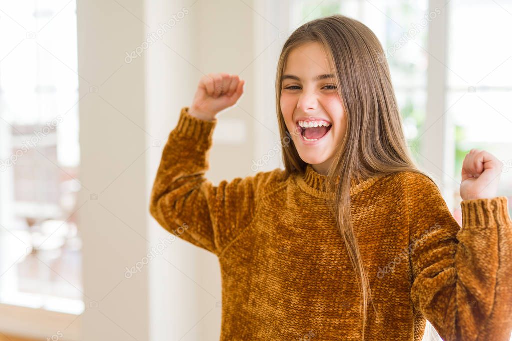 Beautiful young girl kid at home excited for success with arms raised celebrating victory smiling. Winner concept.