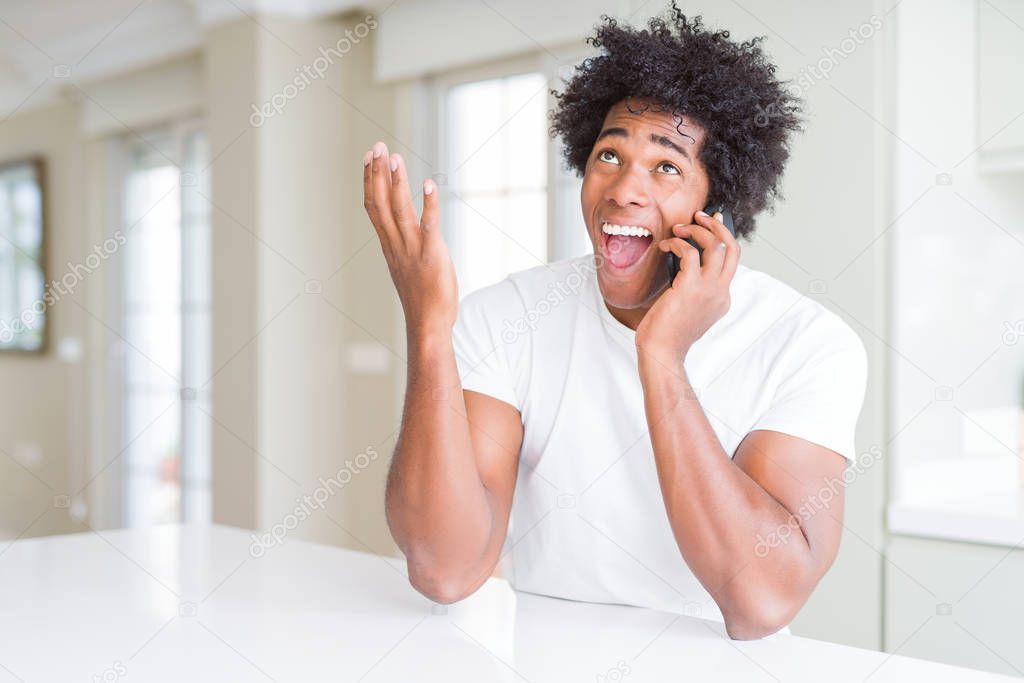 African American business man talking on the phone very happy and excited, winner expression celebrating victory screaming with big smile and raised hands