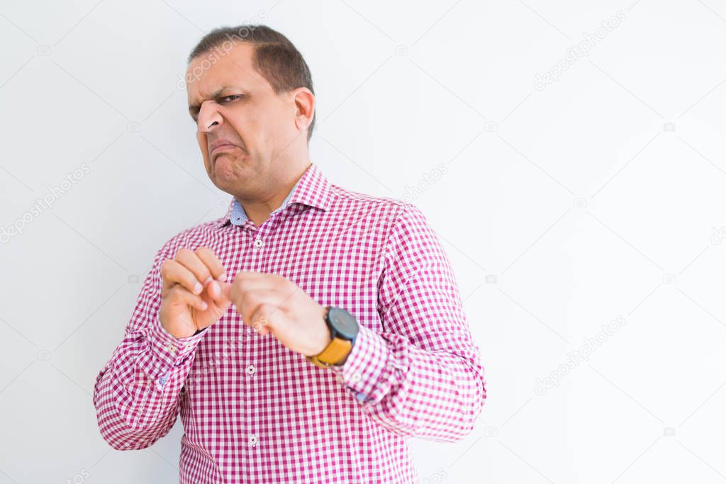 Middle age man wearing business shirt over white wall disgusted expression, displeased and fearful doing disgust face because aversion reaction. With hands raised. Annoying concept.
