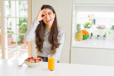 Genç kadın gülümsüyor, parmakları ile mutlu yüz üzerinden seyir göz el ile ok jest yapıyor sabahları sağlıklı kahvaltı yemek.